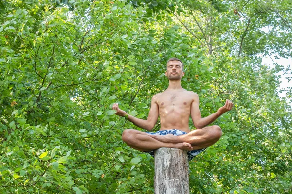 Ung Man Sitter Trädstam Och Mediterar Med Blundande Ögon Och — Stockfoto