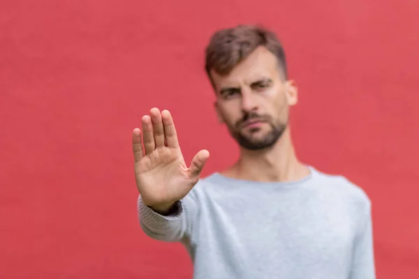 Adam uzak durmak için el hareketi yapıyor. Adam elinle mesafeyi koruyor. Erkek, dur işareti yapıyor. Koronavirüsten korunmak için. Karantina, sosyal mesafe. Eldeki seçici odaklanma