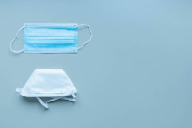 Tek kullanımlık tıbbi maske ve mavi arka planda tek kullanımlık solunum cihazı. Korunmak için doğru tipi seçiyorum. Farklı yüz koruma ürünleri. Virüs koruma konsepti. Üst görünüm, düz görünüm, kopyalama alanı.