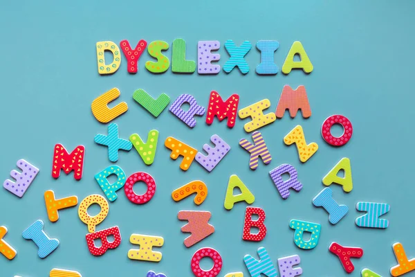 Ahşap harflerden ve dağınık harflerden oluşan disleksi kelimesi. Renkli harflerle yazılmış DYSLEXIA yazısı. Okuma güçlüğü kavramı.