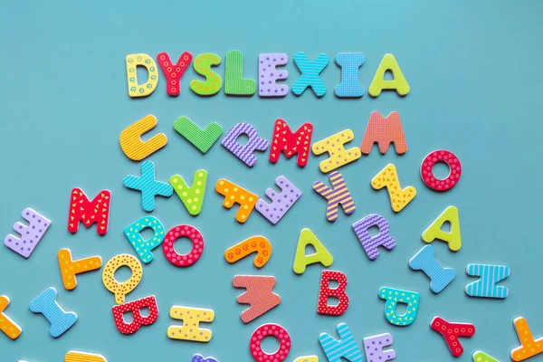 Dyslexia word written of wooden letters and scattered letters below. Inscription DYSLEXIA formed with colorful letters. Reading difficulties concept.