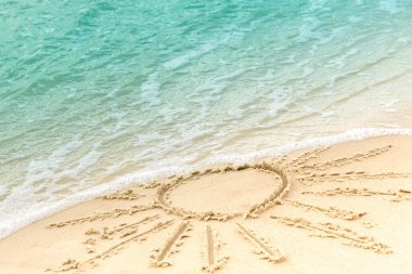 Kumlu sahilde deniz dalgalarını kaplayan güneş sembolü. Yaz tatili konsepti olarak deniz çizimi. Seçici odak