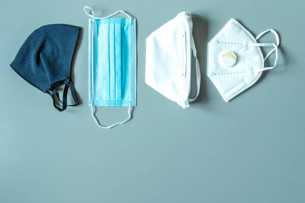 Различные защитные маски на синем фоне с копированием пространства. Многоразовая тканевая маска, одноразовая медицинская маска, респиратор для лица с дыхательным клапаном. Правильный выбор для защиты. Защита вирусов
