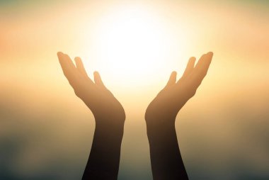 International Day of Yoga concept: Raised hands catching sun on sunset sky clipart