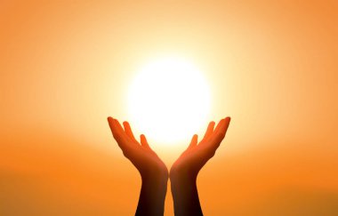 International Day of Yoga concept: Raised hands catching sun on sunset sky clipart