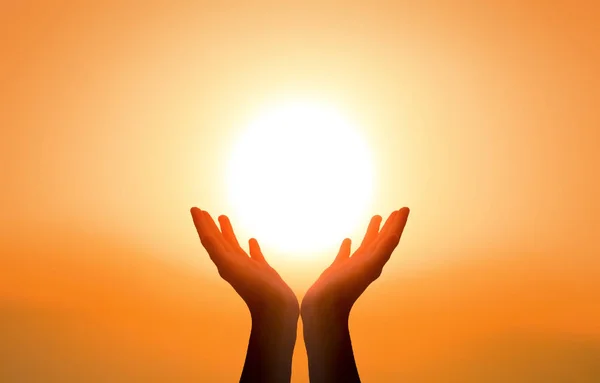 Uluslararası Yoga Günü kavramı: Gün batımında güneşi yakalayan yükseltilmiş eller