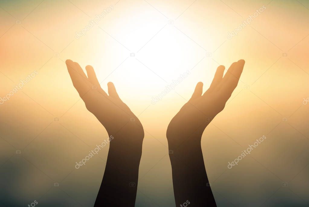 International Day of Yoga concept: Raised hands catching sun on sunset sky