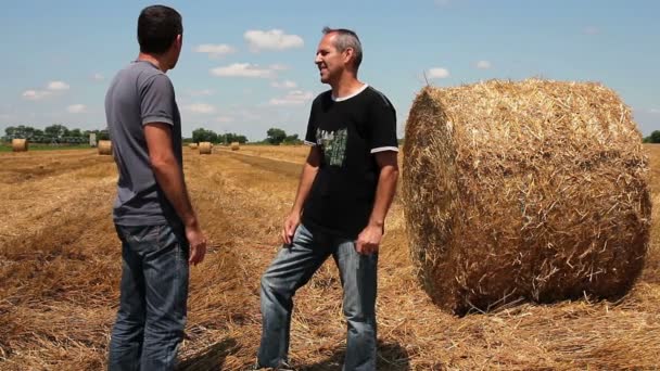 Twee boeren schudden handen op tarweveld tijdens de oogst — Stockvideo