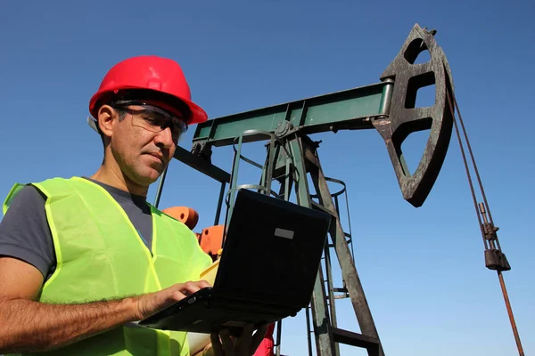 Engenheiro com laptop ao lado de bombear Jack no campo de petróleo — Fotografia de Stock