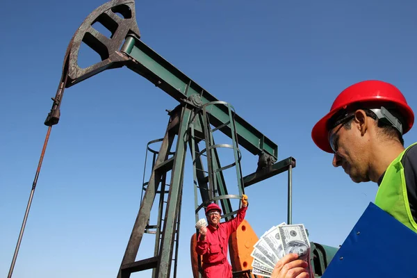 Ropná pole zaměstnanci drží peníze — Stock fotografie