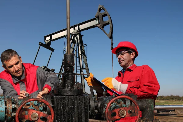 Engenheiros que inspecionam equipamentos de campo de petróleo — Fotografia de Stock