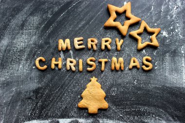 Pişmiş mektuplar Mutlu Noeller, yıldızlar, kar taneleri. Zencefilli tebrik kartı. Tahta masadaki zencefilli ekmekten yapılmış Noel kartı. Fırın tepsisindeki zencefilli kurabiyelerden mutlu noeller.
