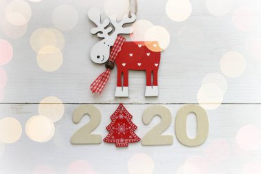 Yeni yılınız kutlu olsun ahşap masa ve beyaz kar taneleri üzerindeki ahşap oda. Uzayı kopyala Noel süsleri. Beyaz ahşap arka planda Noel geyiği, 2020.