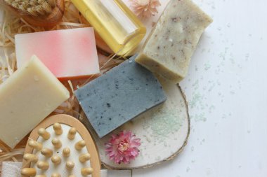 Ahşap arka planda el yapımı doğal sabun. Spa doğal tedavileri. Doğal sabun, vücut fırçası, yağ şişesi ve pamuk havlusu, spa ve sağlık ürünleri ile el yapımı organik sabun..