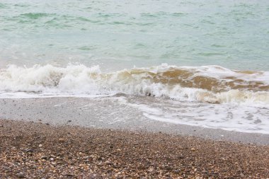 Sahilin arka planında el salla. Güzel, berrak su kıyıya vuruyor. Deniz kıyısındaki dalgalar. 