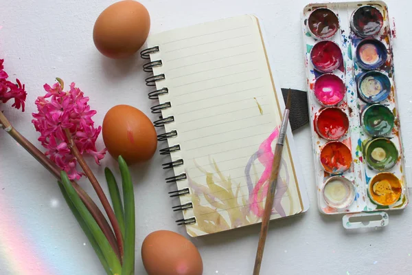 Easter background is beautiful. Paint the eggs with paints and a brush. Creative process. Paint the eggs for Easter. Easter egg on a white background. Copy of the space. Hyacinth flowers, spring.