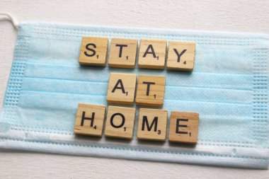 Tahtalar ve maskeler size evde nasıl kalacağınızı söyler. Evde kalmanın güvenli bir konsepti. Covid -19 'dan Coronavirus' a karşı karantina çağrısı. Koronavirüs salgını sırasında sosyal uzaklık kavramı