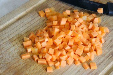 Tahta bir tahtanın üzerinde havuçlar doğranmış. Yemek pişirme süreci.