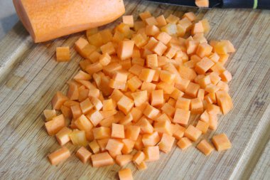 Tahta bir tahtanın üzerinde havuçlar doğranmış. Yemek pişirme süreci.