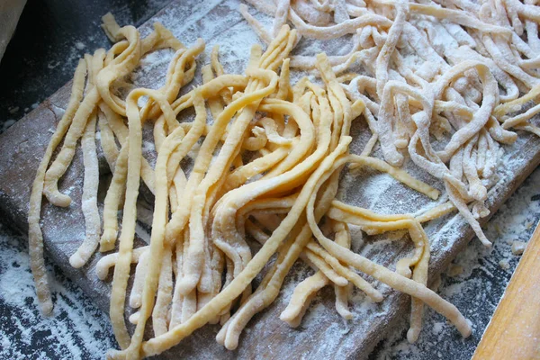 Yumurtalı şehriye, ev yapımı erişte, ahşap masa, üst manzara. Hamurdan ev yapımı erişte yapma süreci. El yapımı erişteler ahşap bir tahtanın üzerinde kurutulur. Yakın çekim, seçici odaklanma