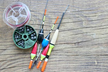 Olta ve olta bobinleri, eski ahşap bir arka planda olta ipiyle boşta. Balık tutmak için şamandıralar ve diğer aksesuarlar..