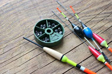 Olta ve olta bobinleri, eski ahşap bir arka planda olta ipiyle boşta. Balık tutmak için şamandıralar ve diğer aksesuarlar..