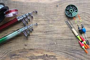 Olta ve olta bobinleri, eski ahşap bir arka planda olta ipiyle boşta. Balık tutmak için şamandıralar ve diğer aksesuarlar..