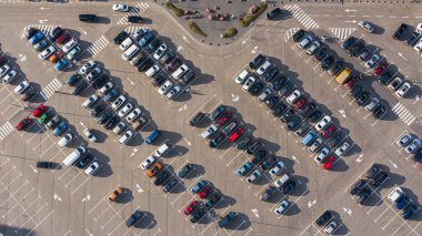 Güneşli bir günde alışveriş merkezinin yanındaki otopark manzarası yükseklikten çekilmiş.