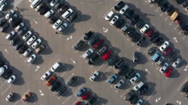 Park yerinin üst manzaralı otoparkı. Drone 'dan hava görüntüsü. Birçok araba hareket ediyor ve park yerinde duruyor. Araba trafiği ve park kavramı.