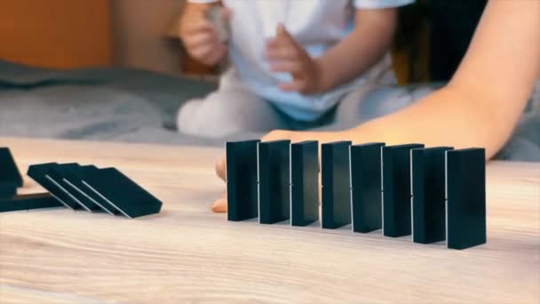 Barn leker hemma i isolering under karantänen: bygga en kedja av fallande dominobrickor. — Stockvideo