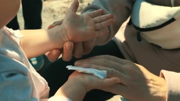 Mother wipes babys hands in the street with disinfectant, alcohol solution and disinfectant napkin — Stock Video