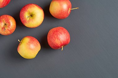 Mutfaktaki eski, koyu çizik beton masaya dağılmış vitamin dolu bir sürü taze olgun elma. Hasat ya da diyet konsepti. Mesaj için yer var. Üst görünüm
