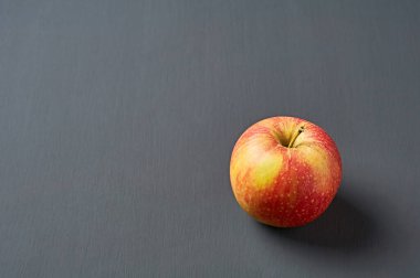 Vitaminlerle dolu taze taze, tek bir elma mutfaktaki eski, koyu çizik beton masanın üzerinde yatıyor. Hasat ya da diyet konsepti. Metin için boşluk