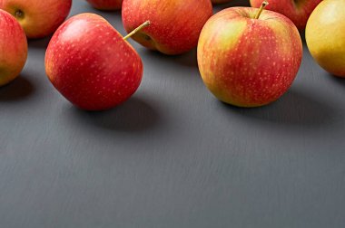 Mutfaktaki eski, koyu çizik beton masaya dağılmış vitamin dolu bir sürü taze olgun elma. Hasat ya da diyet konsepti. Metin için boşluk