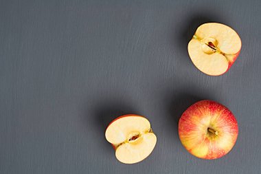 İki yarım, vitamin dolu bir taze kırmızı olgun elma mutfaktaki eski, koyu çizik beton masanın üzerinde yatıyor. Hasat ya da diyet konsepti. Mesaj için yer var. Üst görünüm