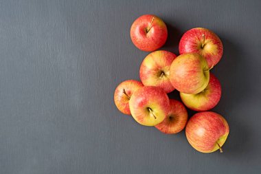 Vitamin dolu taze elmalar yığını mutfaktaki eski, koyu çizik beton masanın üzerinde yatıyor. Hasat ya da diyet konsepti. Mesaj için yer var. Üst görünüm
