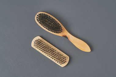 Temizlik bezi, ayakkabı, halı veya diğer tekstil ürünleri için ahşap saplı iki fırça koyu renkli beton masanın üzerinde yatar. Yakın plan.