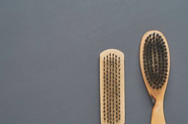 Temizlik bezi, ayakkabı, halı veya diğer tekstil ürünleri için ahşap saplı iki fırça koyu renkli beton masanın üzerinde yatar. Mesaj için yer var. Üst görünüm
