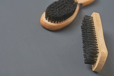 Temizlik bezi, ayakkabı, halı veya diğer tekstil ürünleri için ahşap saplı iki fırça koyu renkli beton masanın üzerinde yatar. Metin için boşluk