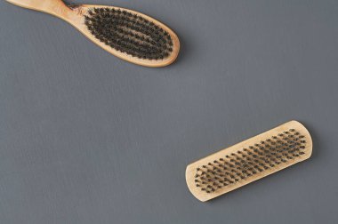 Temizlik bezi, ayakkabı, halı veya diğer tekstil ürünleri için ahşap saplı iki fırça koyu renkli beton masanın üzerinde yatar. Mesaj için yer var. Üst görünüm