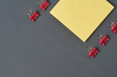 Not almak için boş kare kağıdın yanında kırmızı metal klasörler ofis, okul ya da evdeki koyu beton masanın üzerinde duruyor. Mesaj için yer var. Üst görünüm