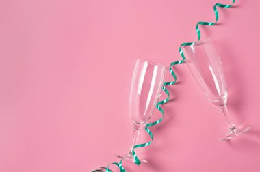 Yeşil spiral kurdelenin yanında alkol için iki boş bardak pembe masanın üzerinde yatıyor. Mesaj için yer var. Üst görünüm