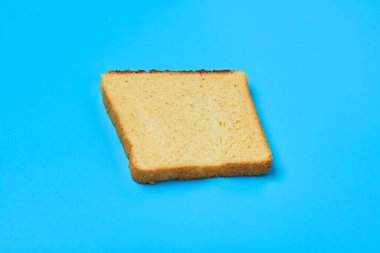 Kızarmış ekmek için bir parça sarı vanilyalı ekmek mutfaktaki mavi masada yatıyor. Yakın plan.