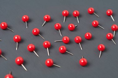 Ofisteki, okuldaki ya da evdeki koyu beton masaya bir sürü kırmızı raptiye serpiştirdim. Yakın plan.