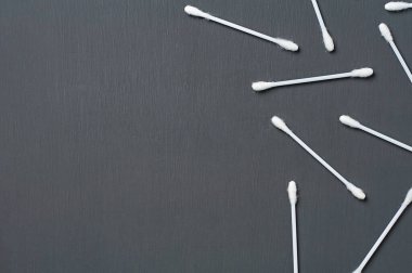 Hijyen için bir sürü yeni pamuk çubuğu koyu beton masanın üzerinde yatıyor. Mesaj için yer var. Üst görünüm