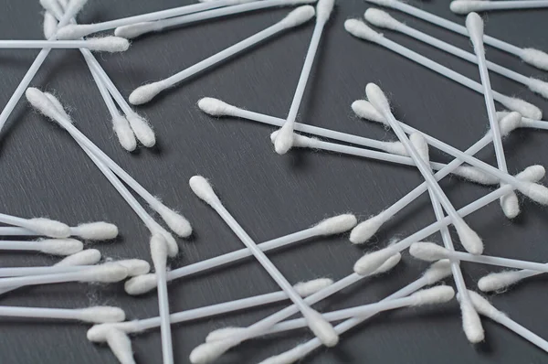Scattered many new cotton sticks for hygiene lies on dark concrete desk. Close-up