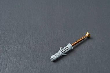 Duvardaki farklı predmeti onarmak için parlak vida rengine sahip yeni bir plastik gri panel atölyedeki koyu beton masada yatıyor. Metin için boşluk