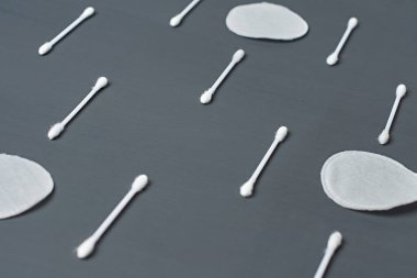 Sıralar dolusu temiz pamuk pedler ve sopalar koyu beton masanın üzerinde yatıyor. Yakın plan.