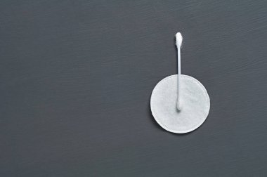 Temiz bir pamuk çubuk ve ped koyu beton masanın üzerinde duruyor. Mesaj için yer var. Üst görünüm