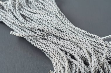 Siyah ve beyaz halat demeti koyu beton masa üzerinde uzanıyor. Yakın plan.